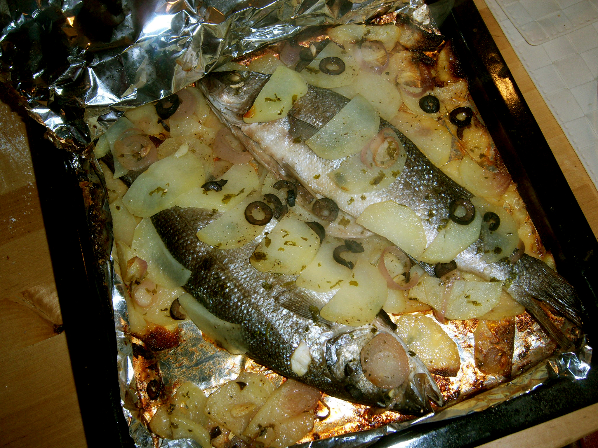 Branzino al cartoccio con patate, scalogno e olive