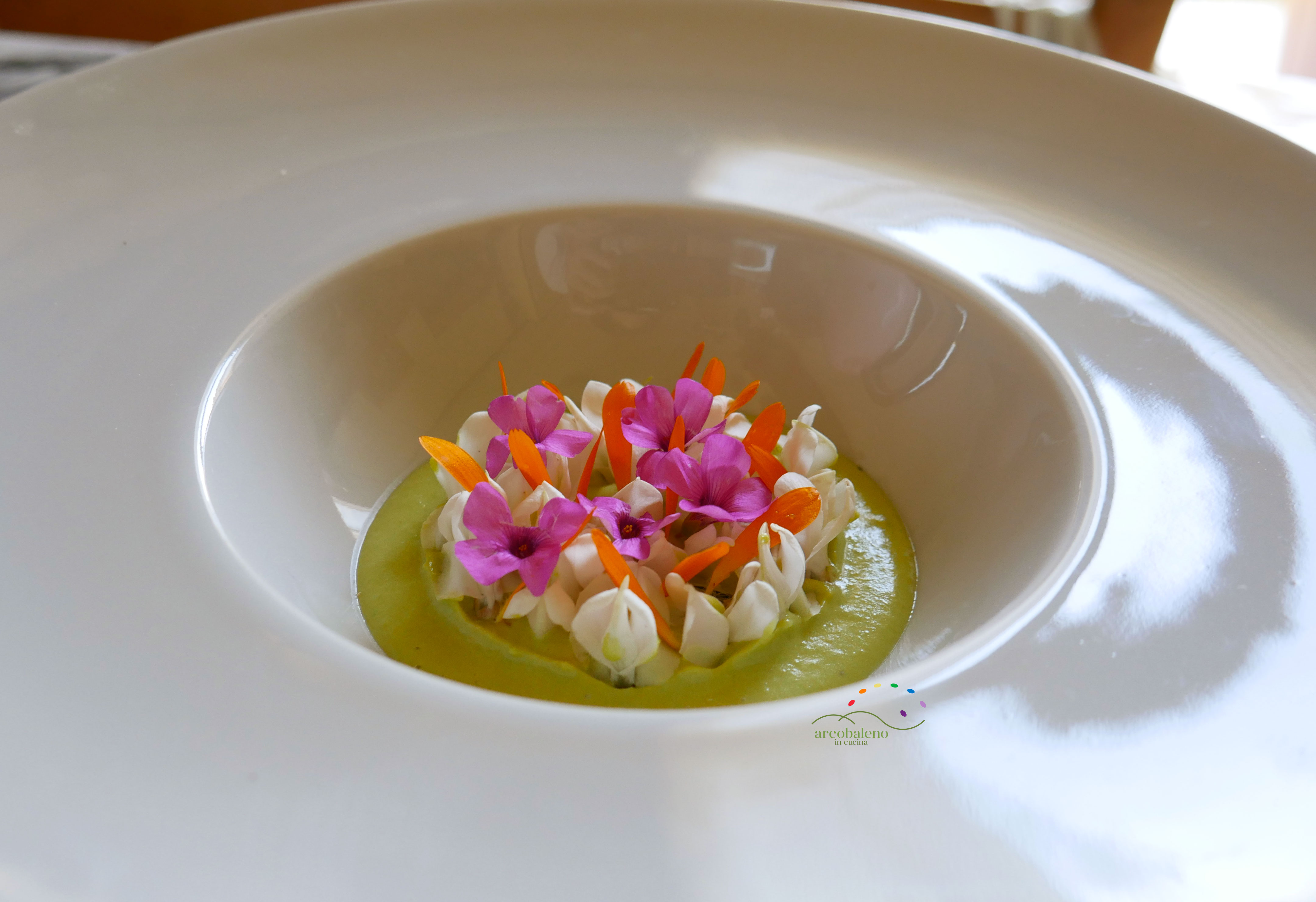Crema fredda di piselli e anacardi guarnita con fiori di acacia, calendula e acetosella