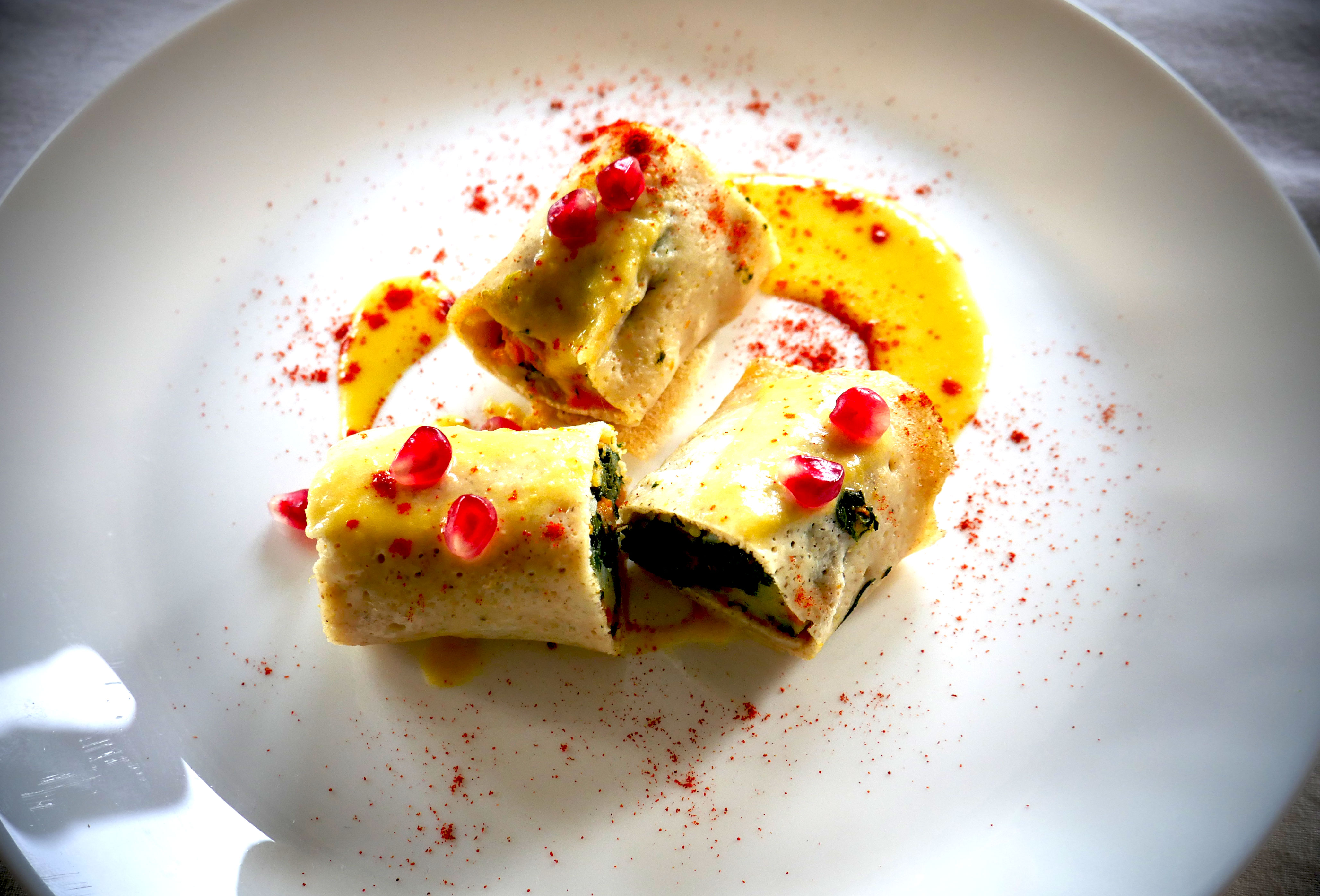 Crepes salate al forno farcite con zucca e bietole, guarnite con crema di ceci e chicchi di melagrana, paprika dolce
