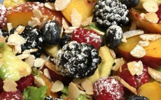 Macedonia con avocado, frutti di bosco, fichi, pesche e mandorle tostate