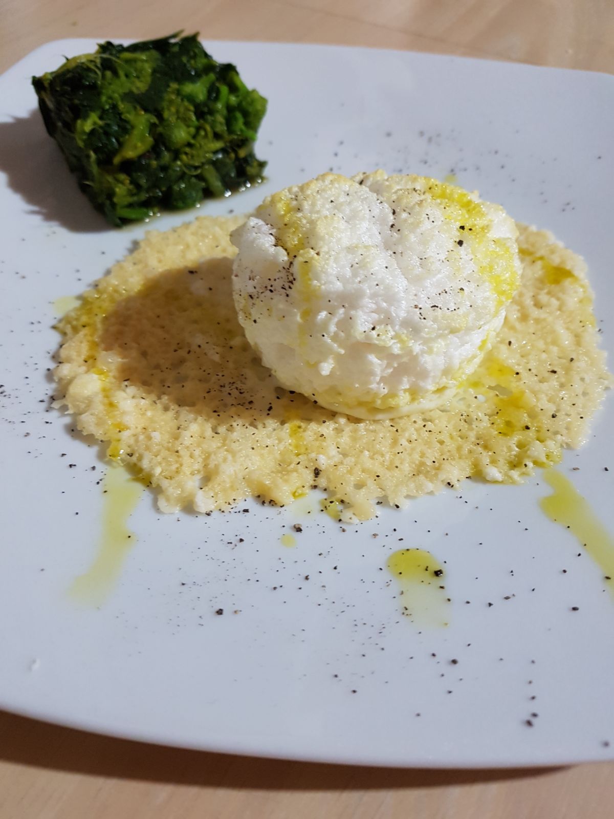 Nuvola di uovo fondente su cialda di parmigiano e guarnizione di friarielli