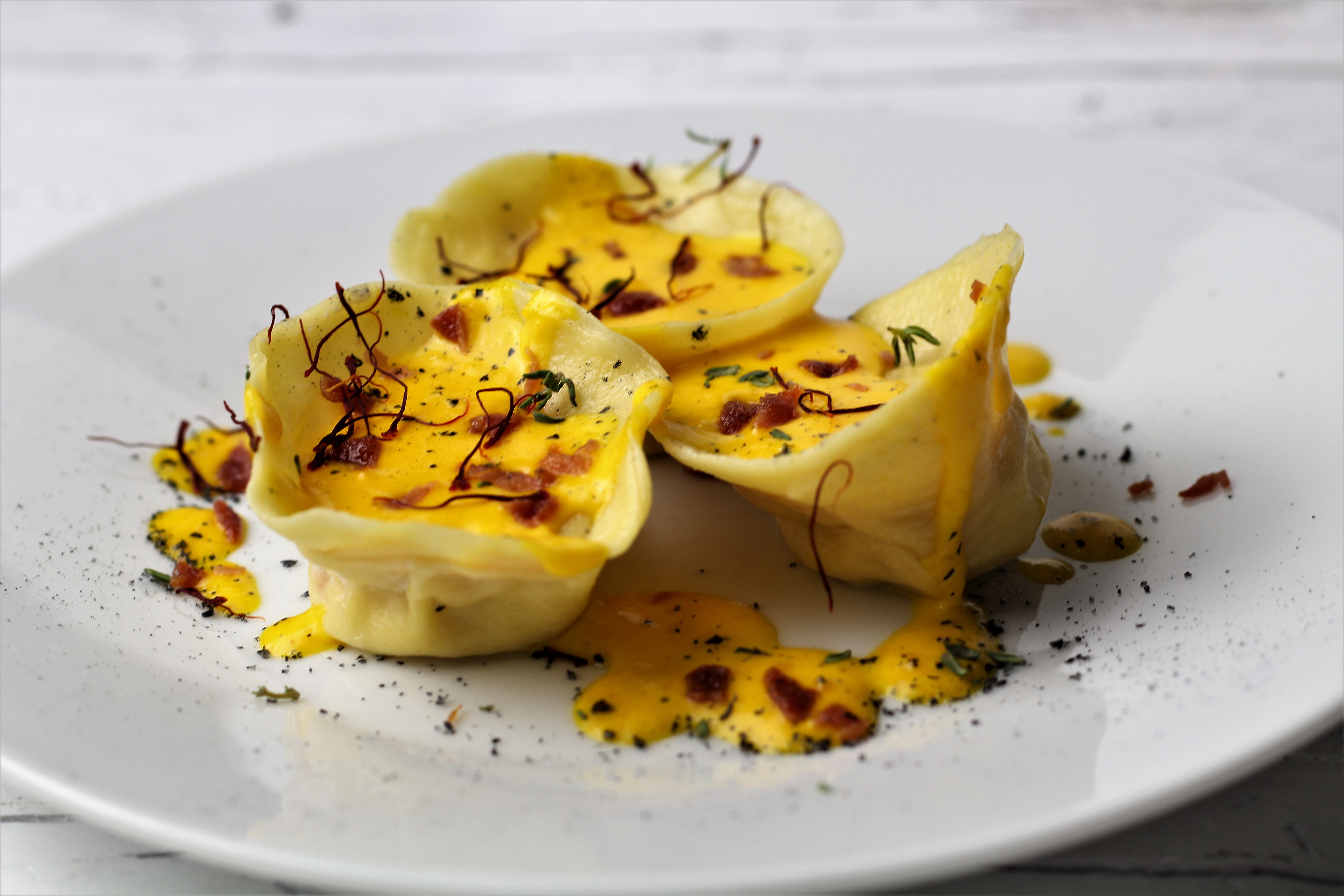 Ravioli ai gamberi con crema allo zafferano zaffy e briociole di bacon