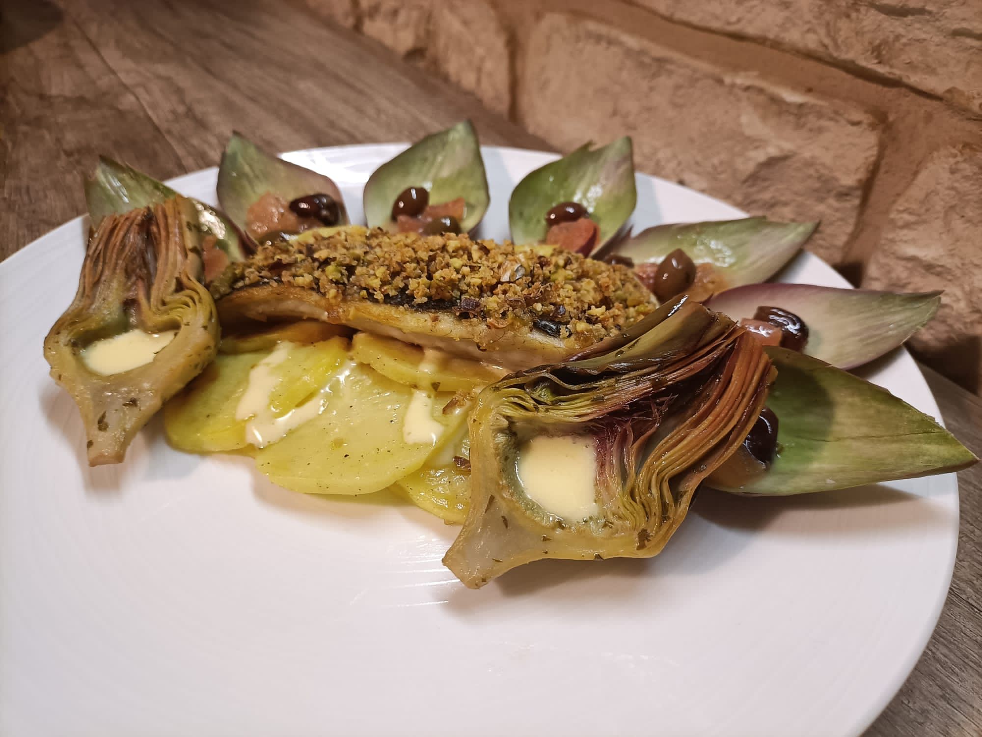 Spigola alla vernaccia in crosta di pistacchi su letto di patate, carciofi e maionese