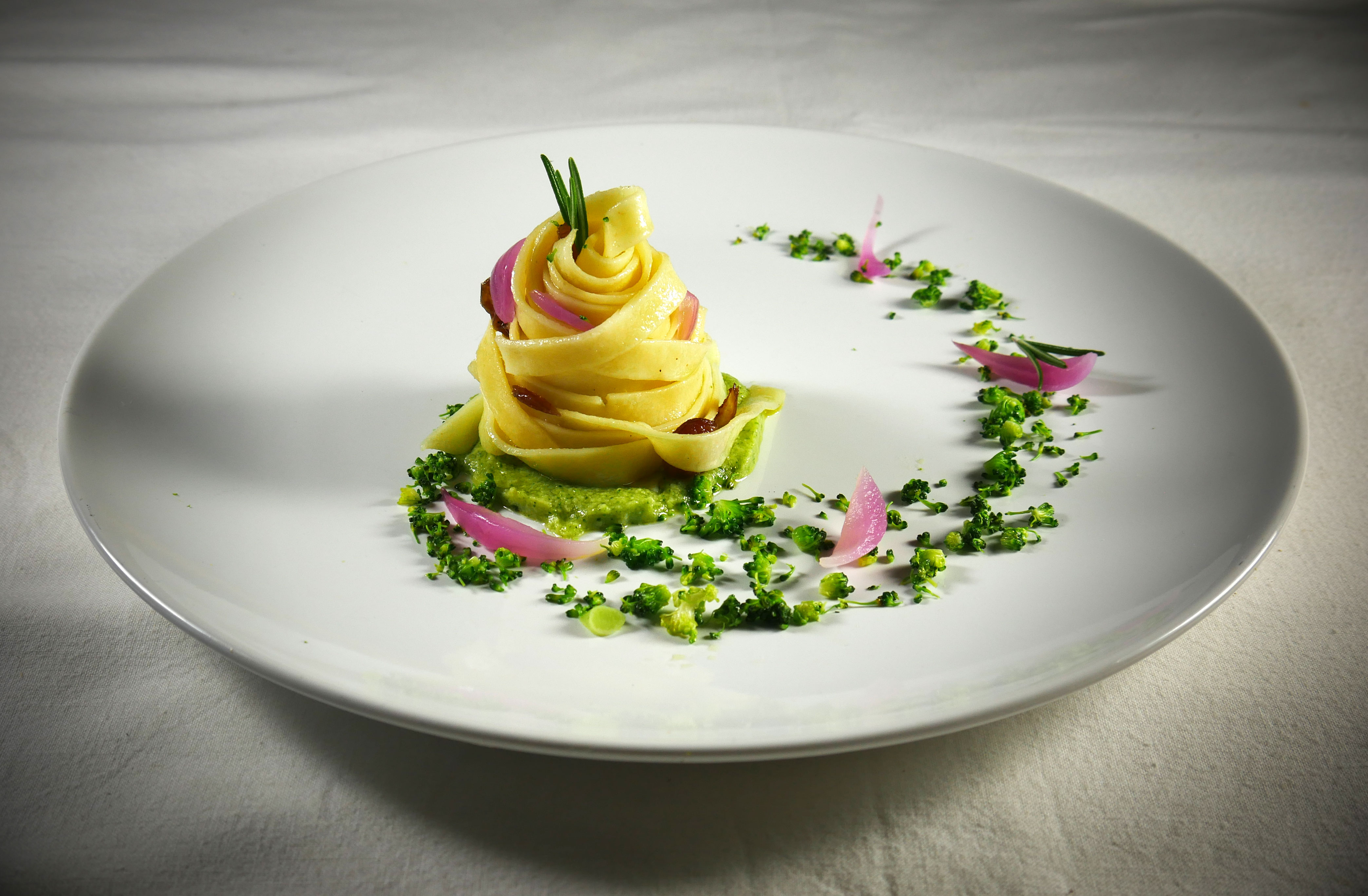 Tagliatelle vegan con crema di broccoli e patate, uvetta e cipolla rossa profumate con zenzero e rosmarino