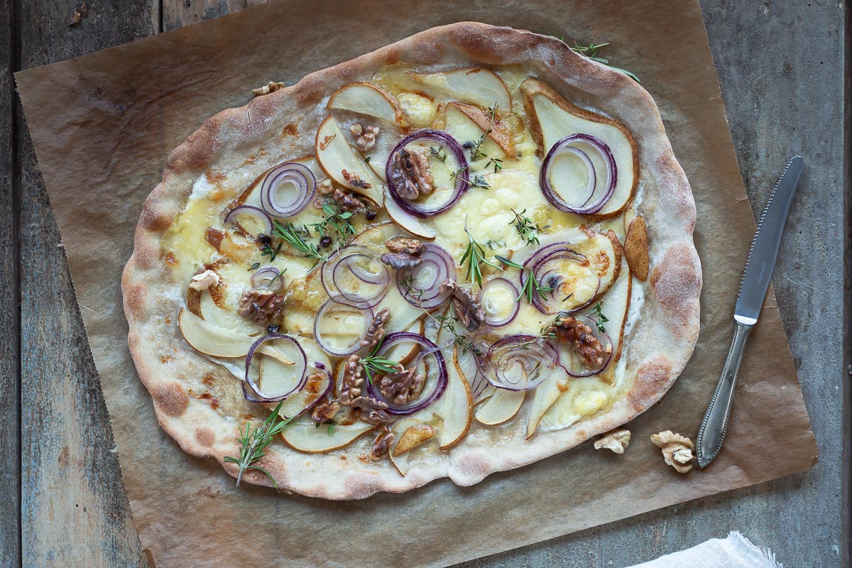 Tarte flambee con pere, formaggio d’alpeggio, cipolle e noci.