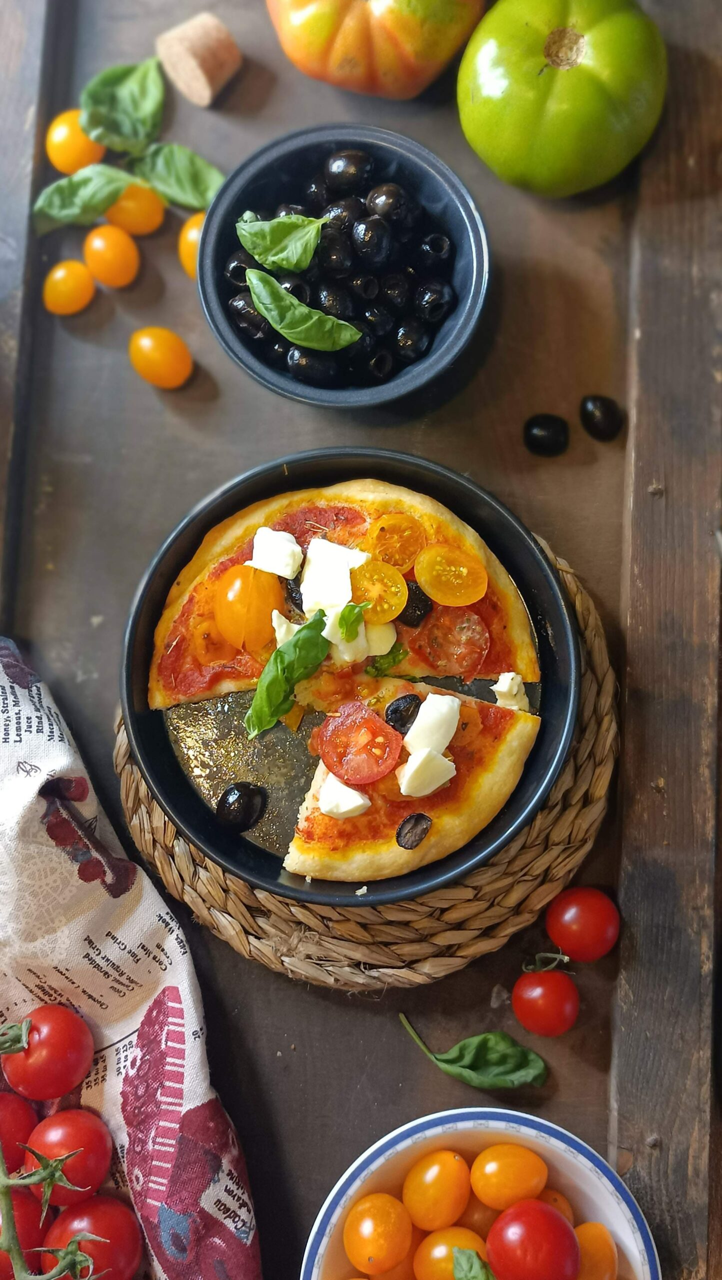 Pizza con pomodorini gialli,rossi, mozzarella di bufala e olive nere