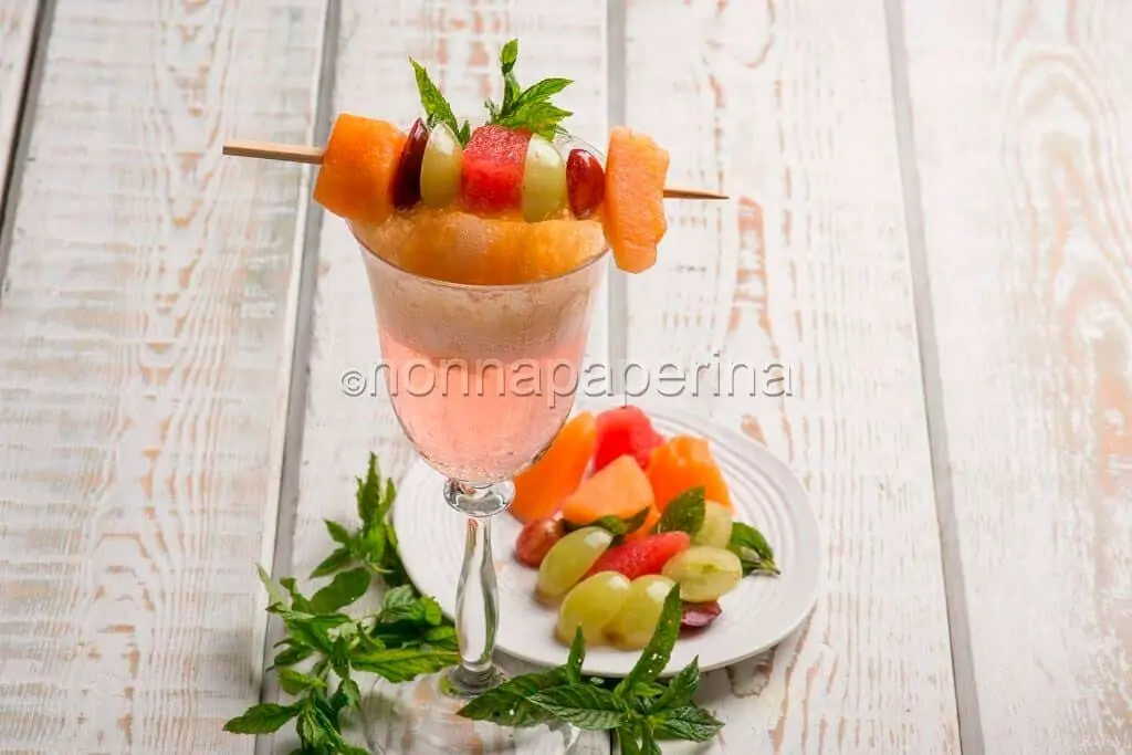 Aperitivo con bollicine, spuma di pesca e spiedino di frutta frizzante